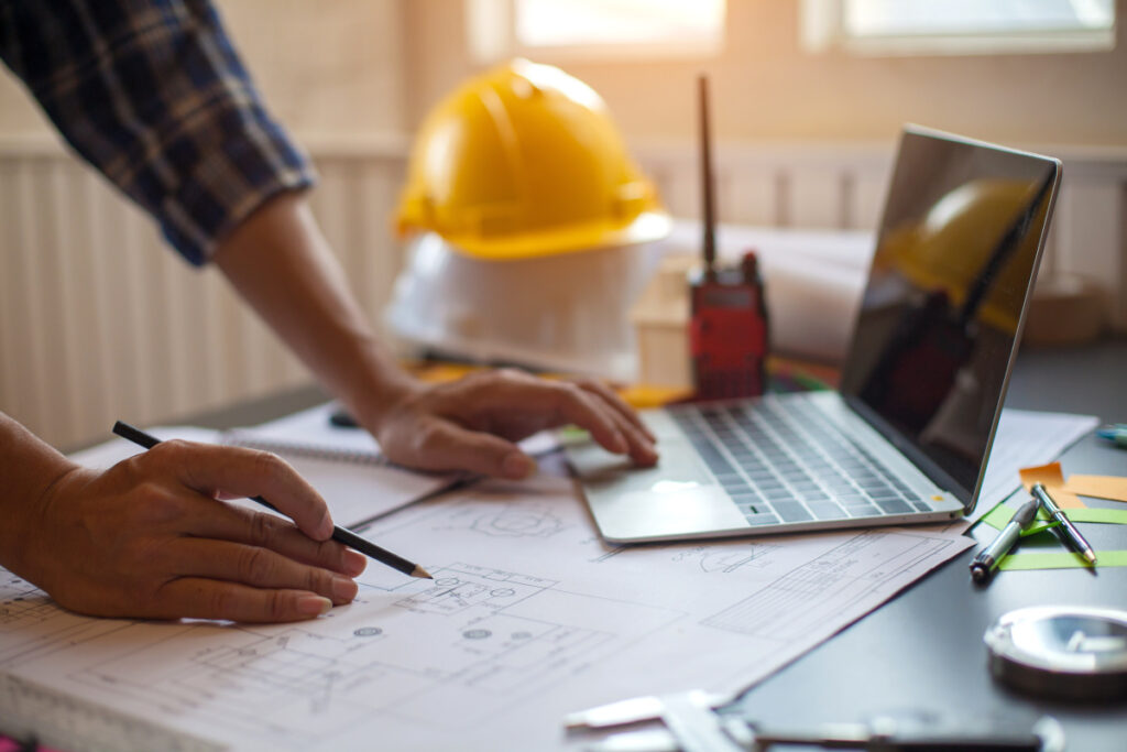 Ingenieur arbeitet an Plänen in Vermessungsbüro.  